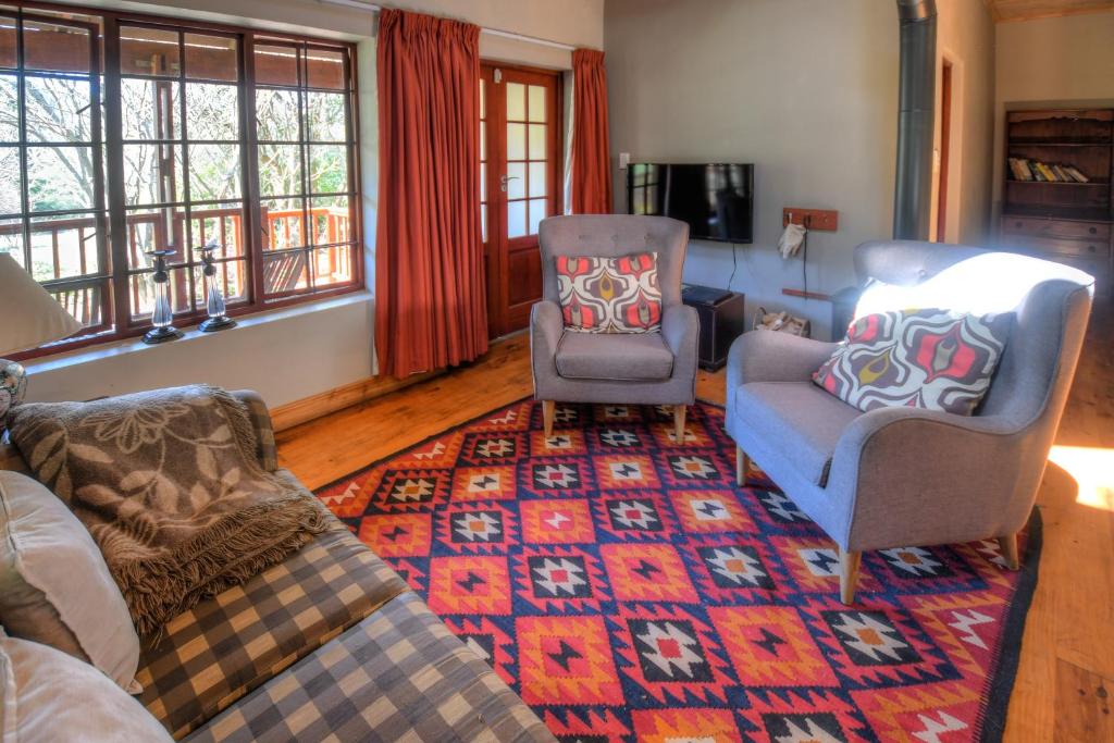 sala de estar con sofá, 2 sillas y alfombra en Laragh-on-Hogsback, en Hogsback