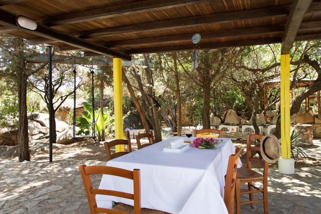 a table with a white tablecloth and chairs under a pergola at Acqua Marina in Monte Petrosu