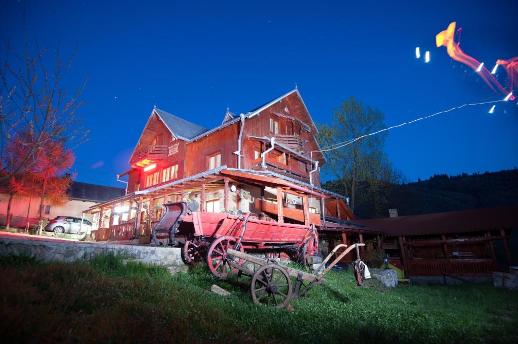 a large wooden house with a wagon in front of it at Pension Lucia Bucovina in Vama