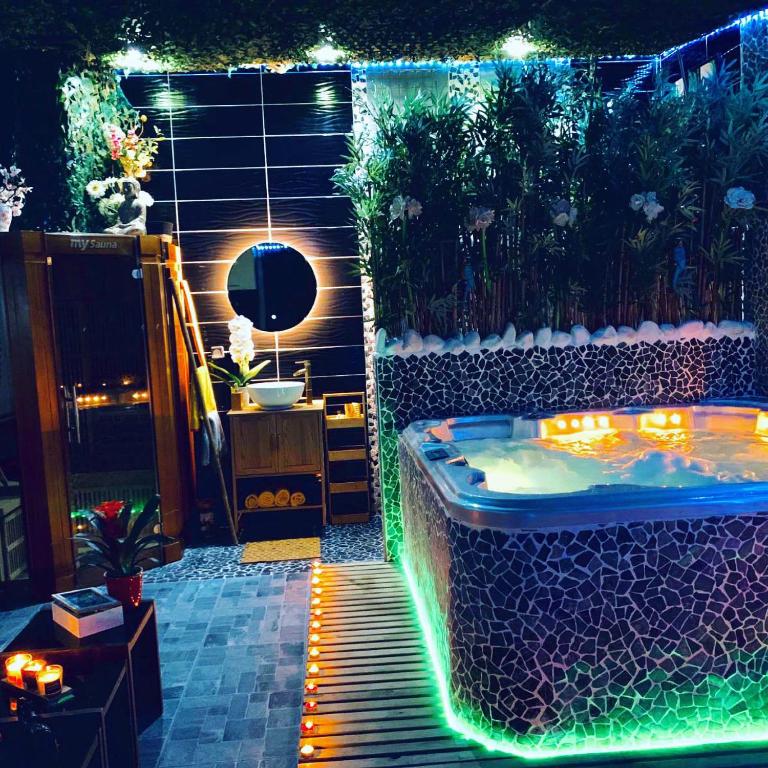 a jacuzzi tub in a garden with lights at Jungle Vibes - Jacuzzi - Sauna in Yerres