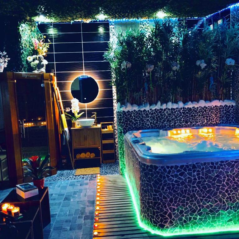 Jungle Vibes - Jacuzzi - Sauna في Yerres: حوض جاكوزي في حديقة مع أضواء