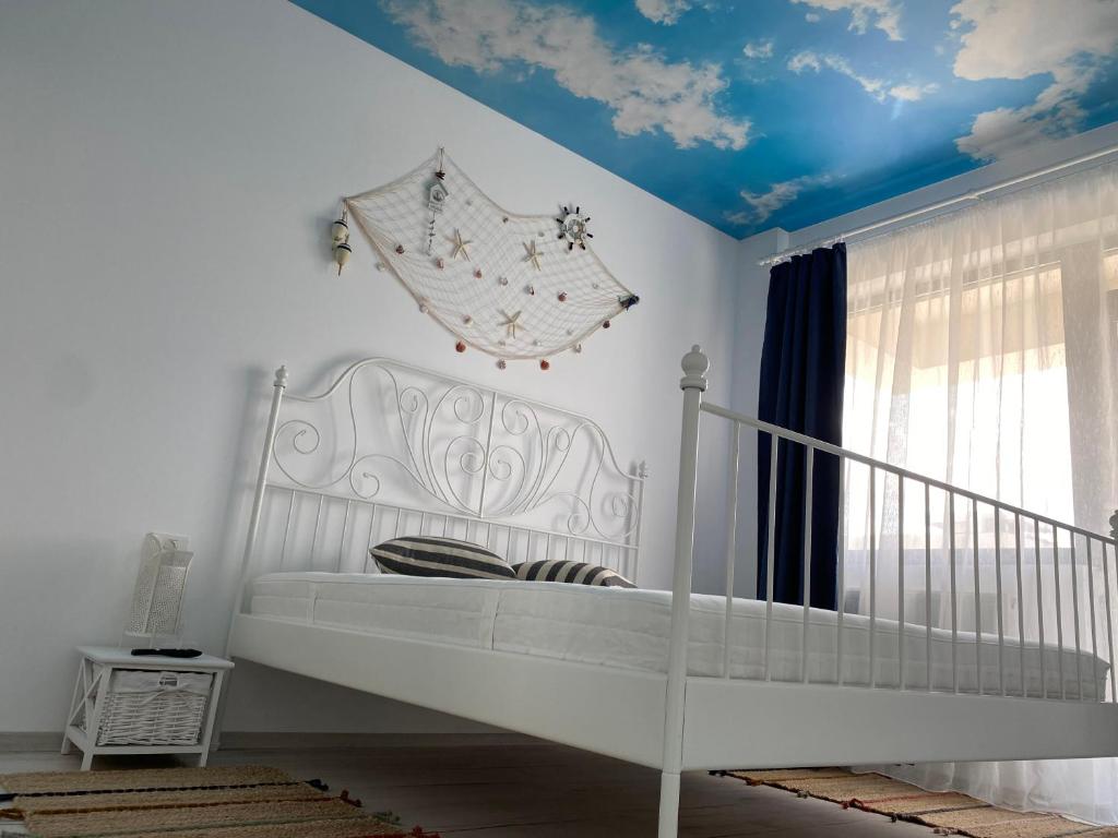 a bedroom with a white bed and a blue ceiling at Ela's Apartment in Mamaia Sat/Năvodari