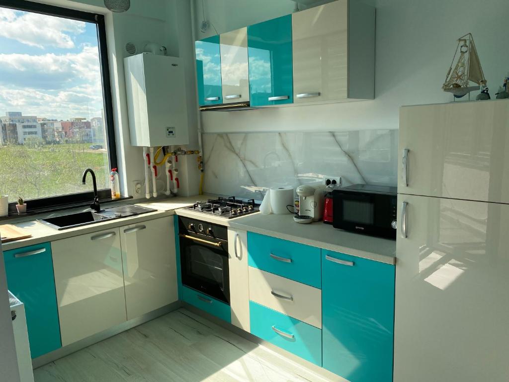 a kitchen with blue and white cabinets and a refrigerator at Ela's Apartment in Mamaia Sat/Năvodari