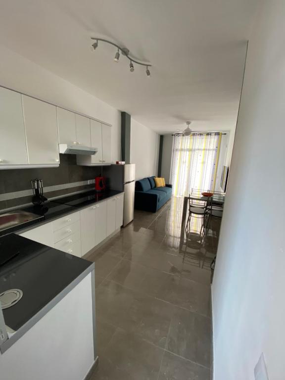 a kitchen with white cabinets and a living room at Coconoa Beach in Playa del Ingles