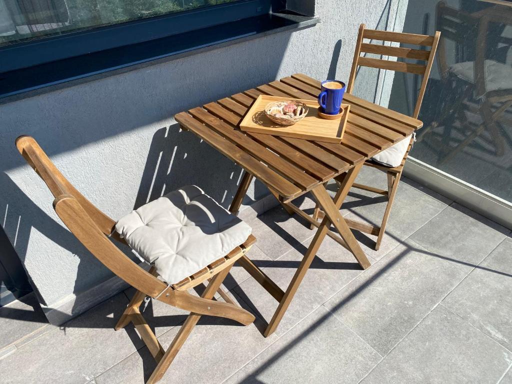 a wooden table and chair with a plate of food at Ela's Apartment in Mamaia Sat/Năvodari