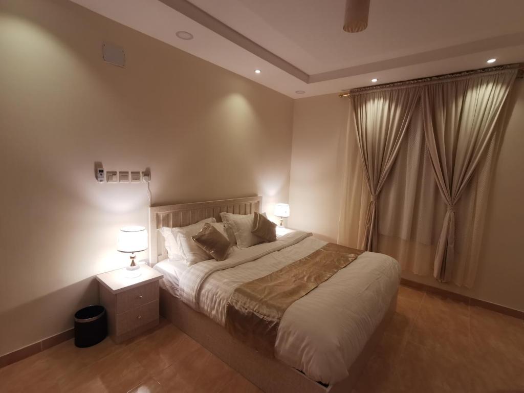 a bedroom with a bed with two lamps and a window at المبيت للشقق الفندقية in Sirr Āl Ghalīz̧