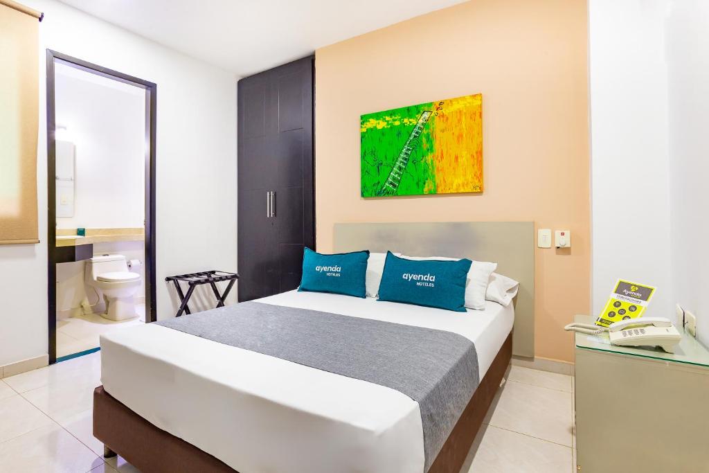 a bedroom with a large bed with blue pillows at Hotel Ayenda Monteria Central in Montería