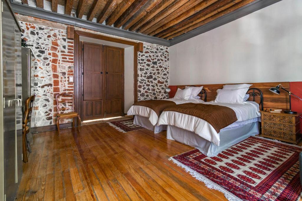 a bedroom with two beds and a brick wall at CASA SAUTO Luxury Suite in Downtown in Mexico City