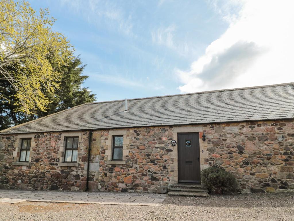 an old stone building with a black door at Cherryburn Cottage in Wooler