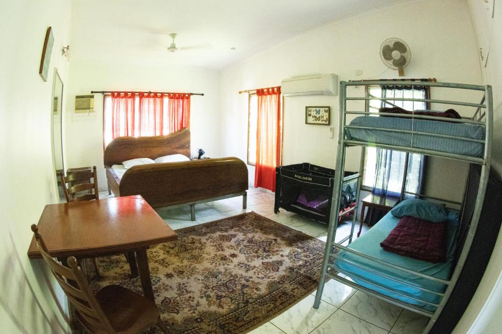 a room with two bunk beds and a table and a desk at Batchelor Butterfly Farm in Batchelor