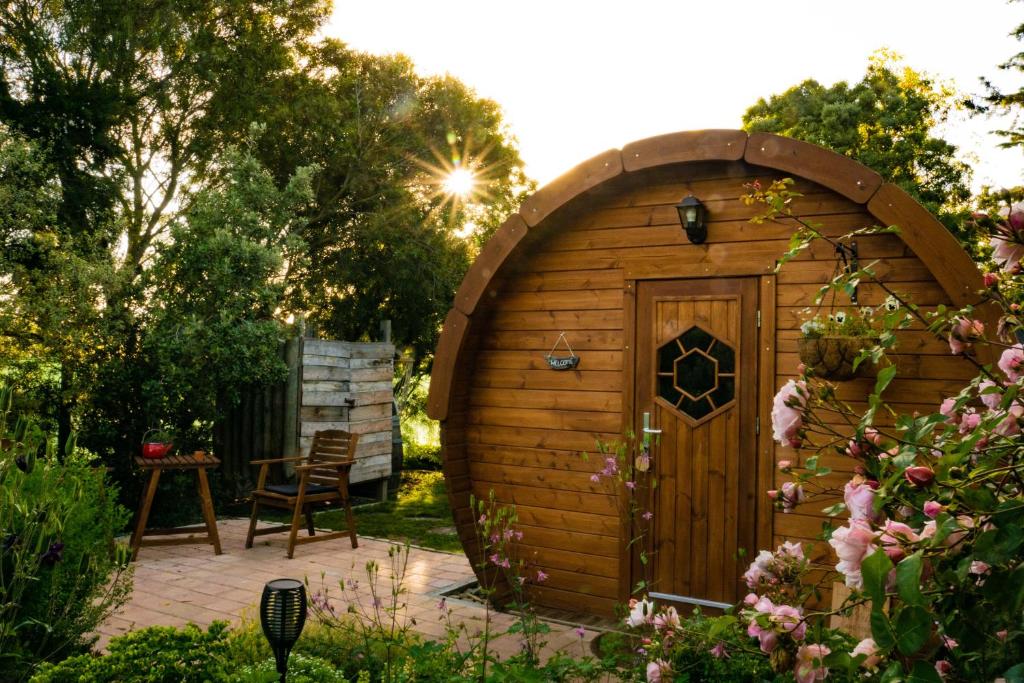a small wooden shed with a door in a garden at Marlborough Wine Barrel Cabins in Blenheim