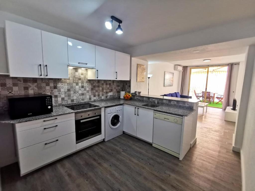 uma cozinha com armários brancos e uma máquina de lavar louça em Cosy apartment Arenal Bol em Calpe