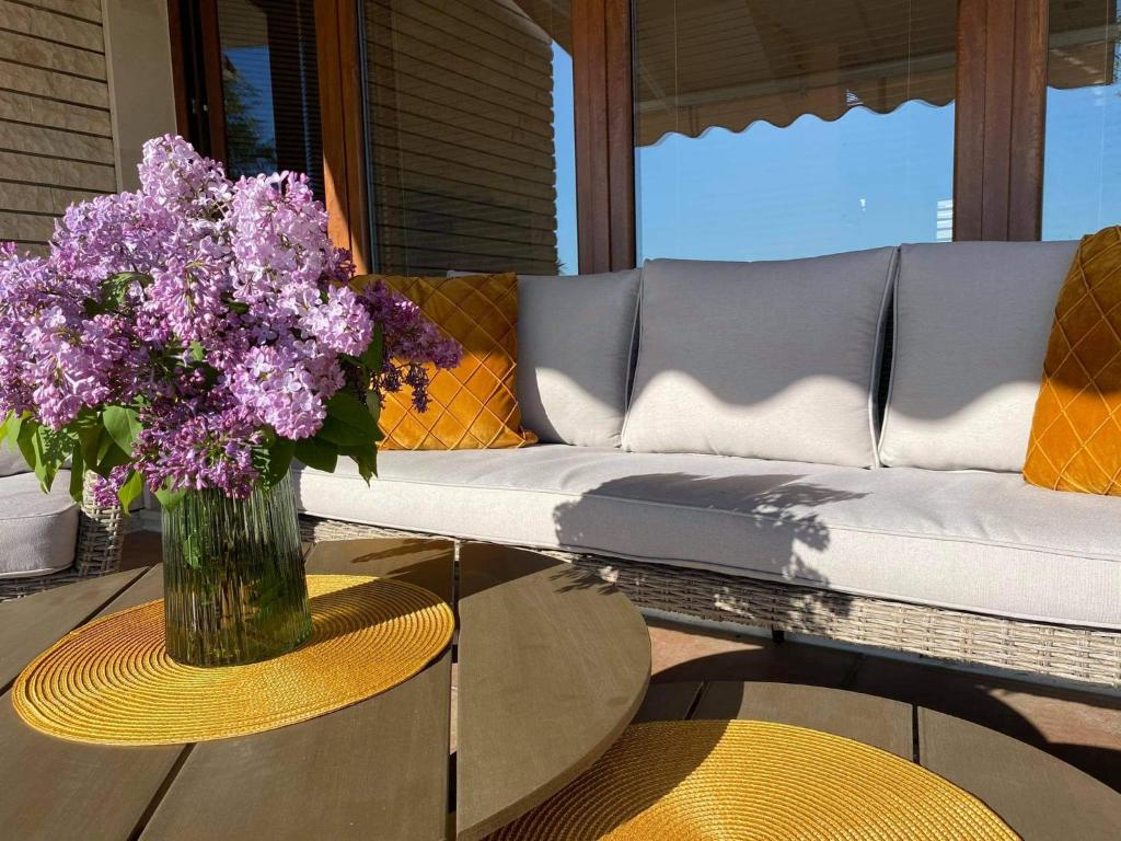 a vase of purple flowers on a table next to a couch at Sunrise Lighthouse Golf Private Villa in Balchik