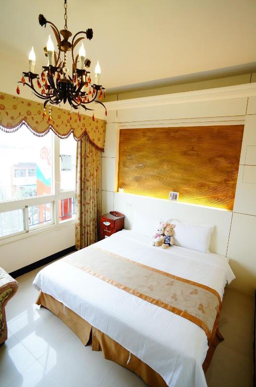 a bedroom with a large bed and a chandelier at 洄瀾雅舍民宿-近火車站-東大門夜市附近 in Hualien City