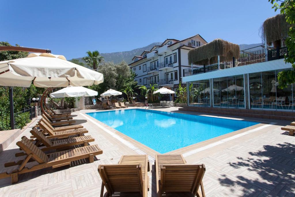a swimming pool with chairs and umbrellas next to a building at Green Peace Hotel in Oludeniz