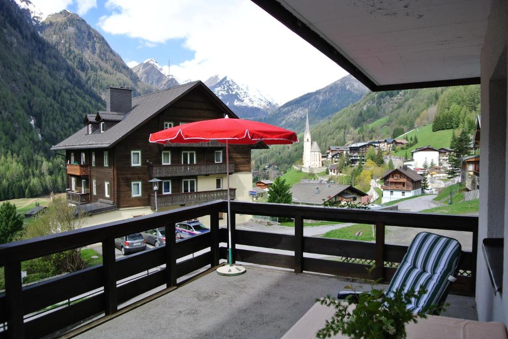 einen Balkon mit einem roten Regenschirm und einem Haus in der Unterkunft Appartement Gorgasser im Berghaus Glockner in Heiligenblut