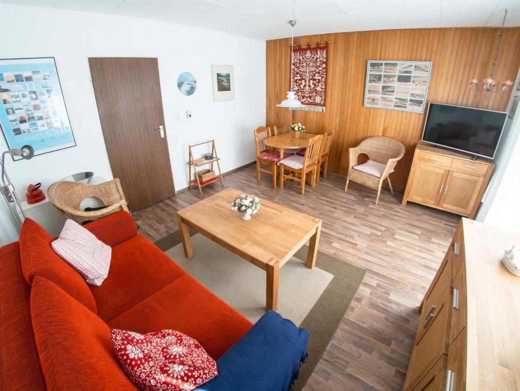 sala de estar con sofá rojo y mesa en Sandkamp 4, Ferienwohnung 28 en Sankt Peter-Ording