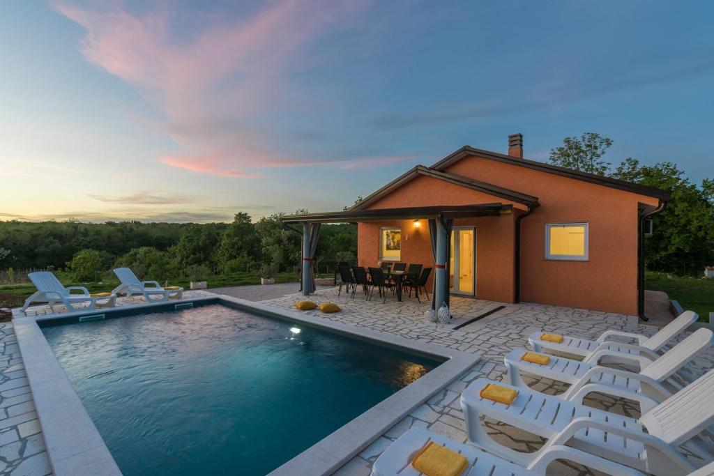 a swimming pool with chairs and a house at Villa Pendolina with Private Pool in Buje