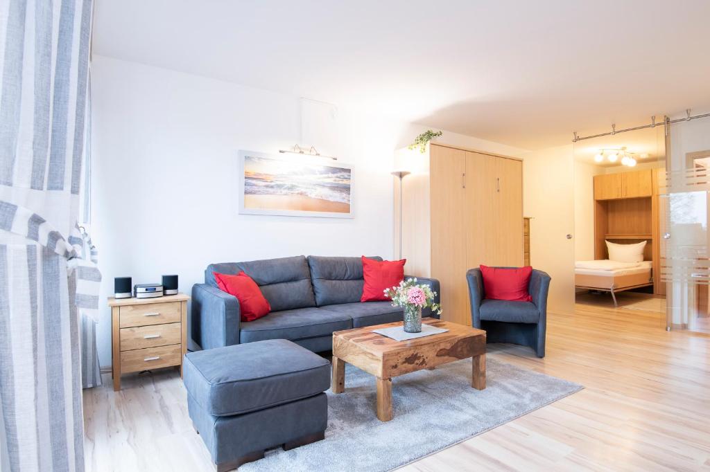 ein Wohnzimmer mit einem blauen Sofa und roten Kissen in der Unterkunft Hamburger Straße 11 Wohnung 9 in Kellenhusen