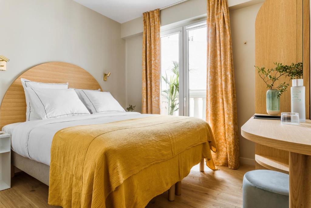 a bedroom with a bed with a yellow blanket on it at Hôtel AMI - Orso Hotels in Paris