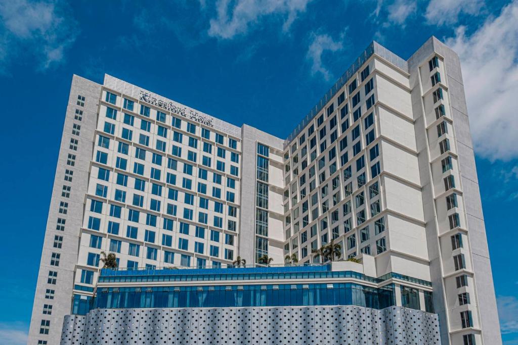 zwei hohe weiße Gebäude gegen einen blauen Himmel in der Unterkunft Kingsford Hotel Manila in Manila