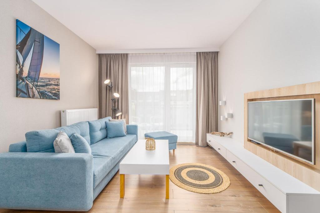 a living room with a blue couch and a tv at Bel Mare Resort Apartment with Parking by Renters in Międzyzdroje