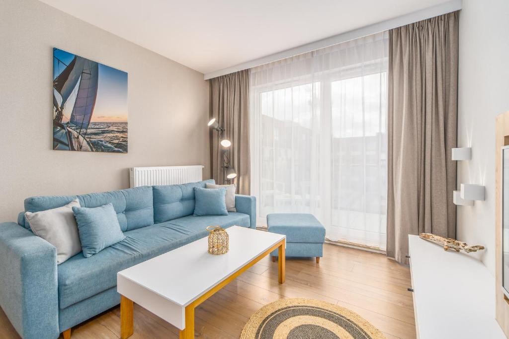a living room with a blue couch and a table at Bel Mare Resort Apartment with Parking by Renters in Międzyzdroje