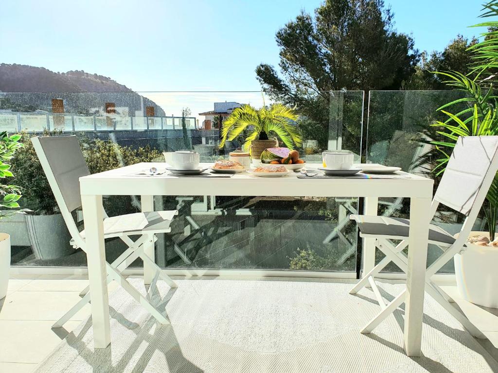 una mesa blanca y 2 sillas en el patio en Brand New CalaDoy at 150 meters from Canyamel Beach, Pool & Garden, Solarium en Canyamel