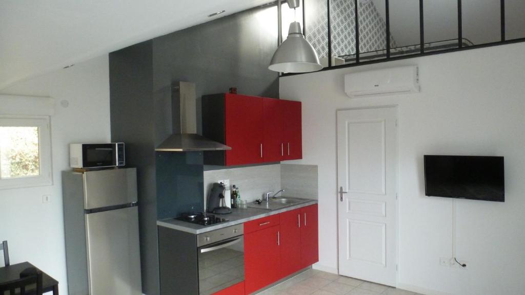 een keuken met rode kasten en een koelkast bij Logements Le232 fr in Chasseneuil-du-Poitou