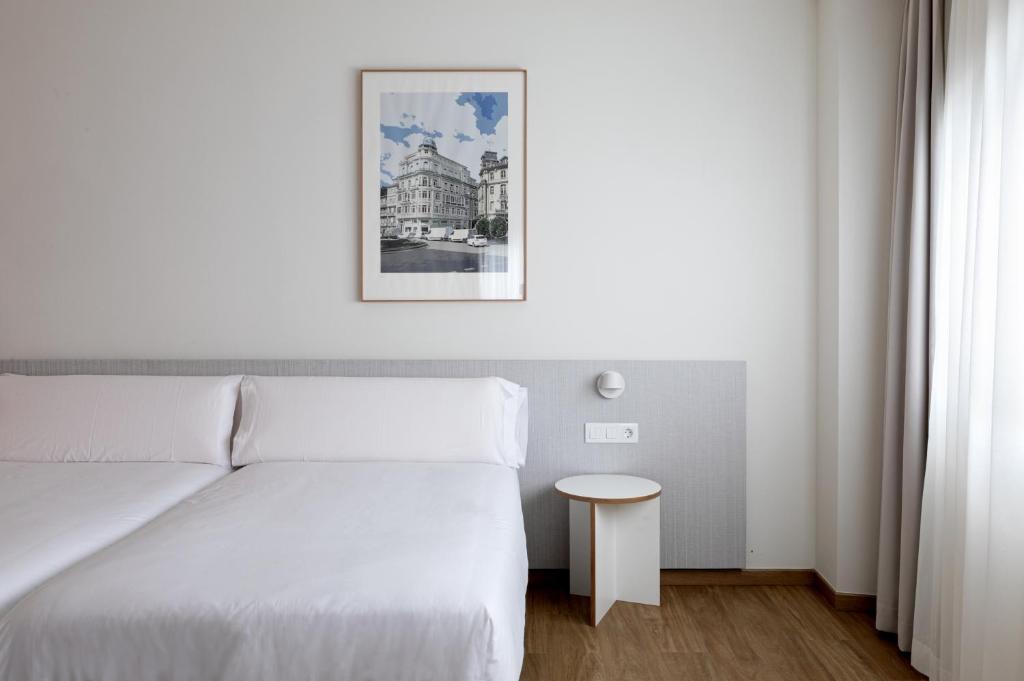 1 dormitorio con cama blanca y mesa en Apartamentos Forum Ceao, en Lugo