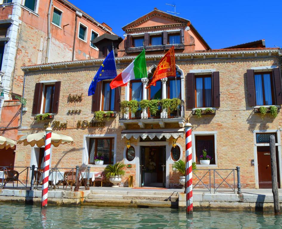 a building on the water with flags in front of it at Ai Mori d'Oriente in Venice