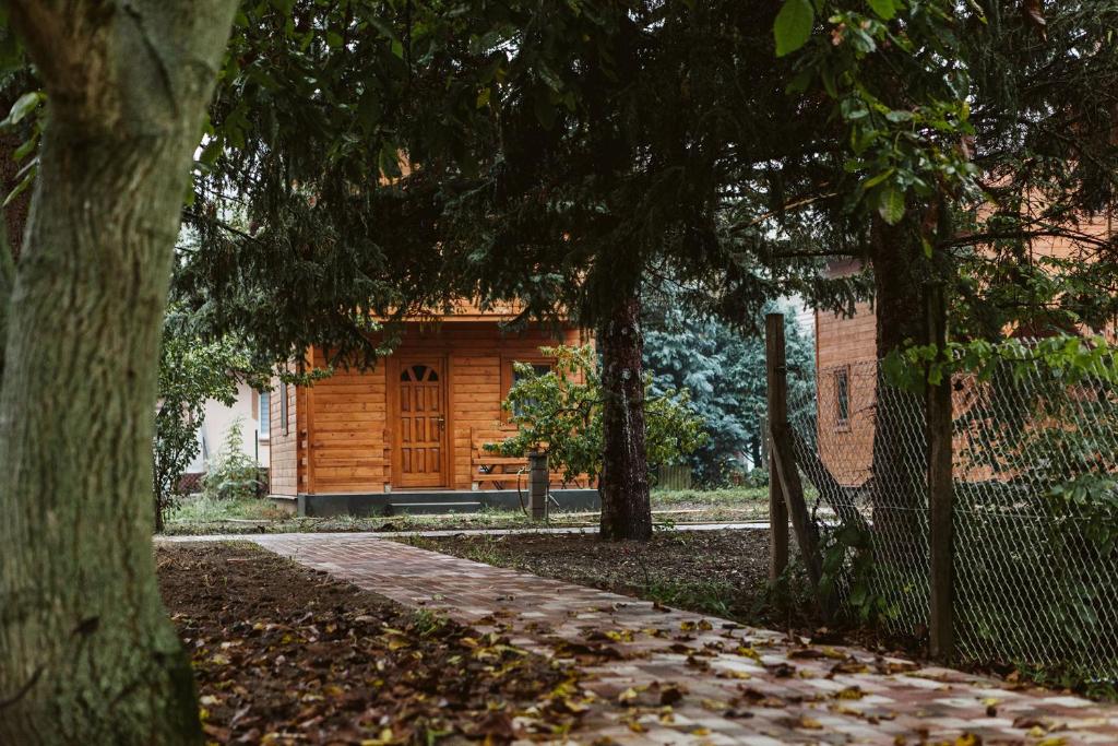 une cabane en rondins dans un parc avec des arbres et une passerelle dans l'établissement MINARDI vendégházak, à Berekfürdő