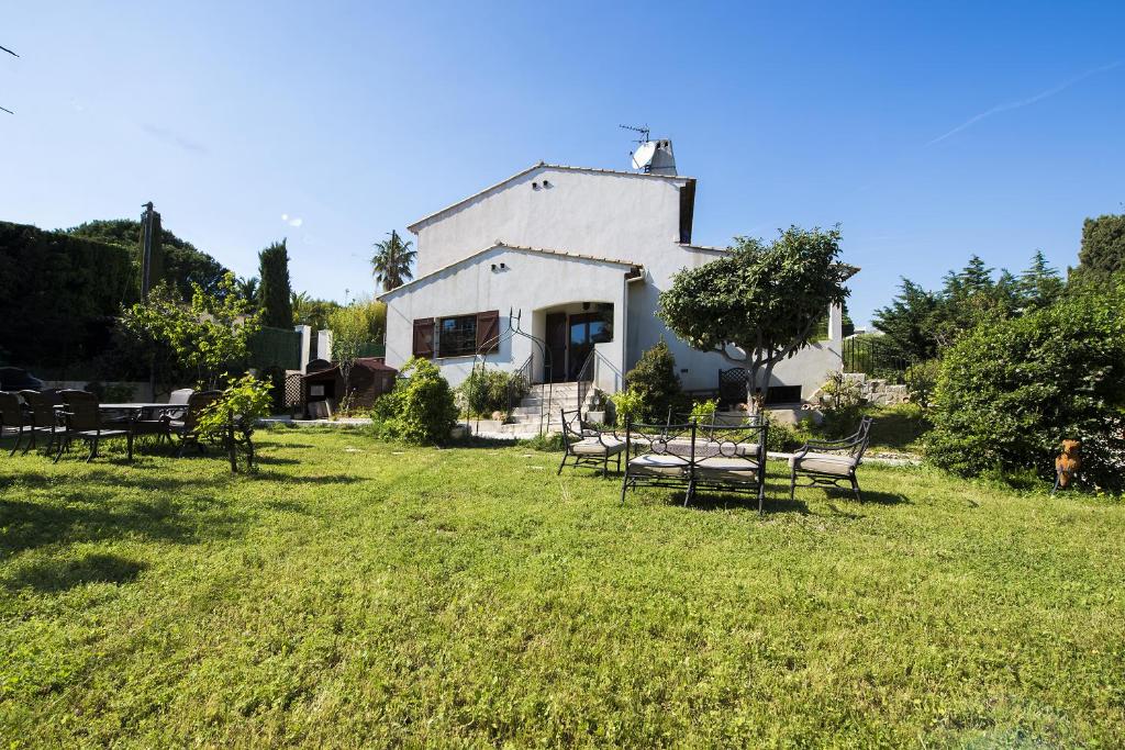 una casa blanca con bancos en el césped en Villa Eden en Antibes