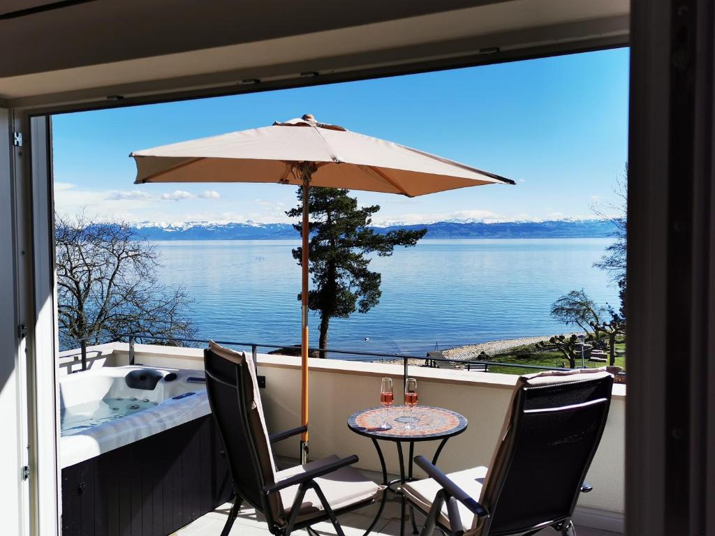 a patio table with an umbrella on a balcony at Uferloft in Immenstaad am Bodensee