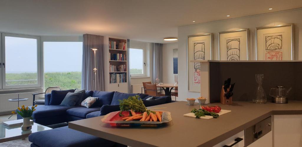 een woonkamer met een blauwe bank en een tafel bij Zeewaarts in Cadzand-Bad in Cadzand-Bad