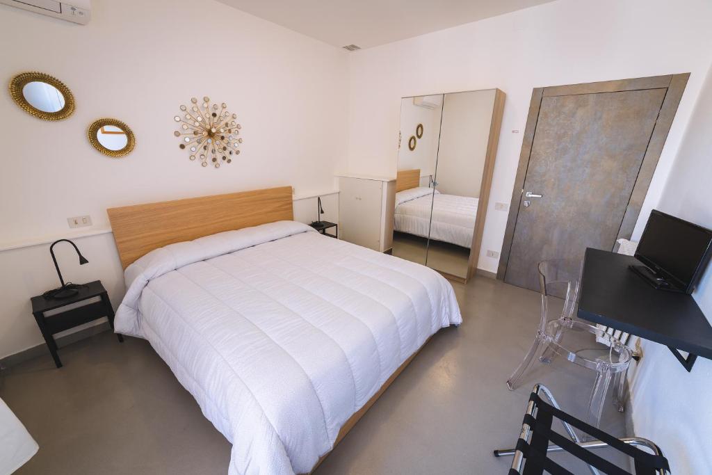 a bedroom with a bed and a desk and a mirror at LOCANDA Roma sleep & food in Donoratico