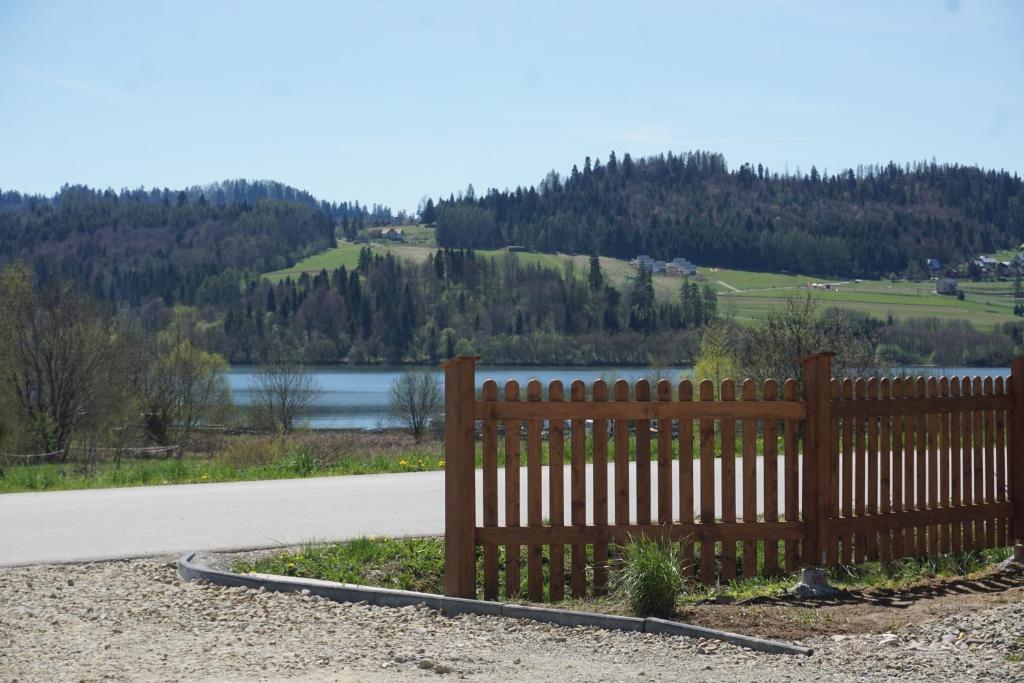 a fence on the side of a road next to a lake at Dom Podróżnika in Maniowy