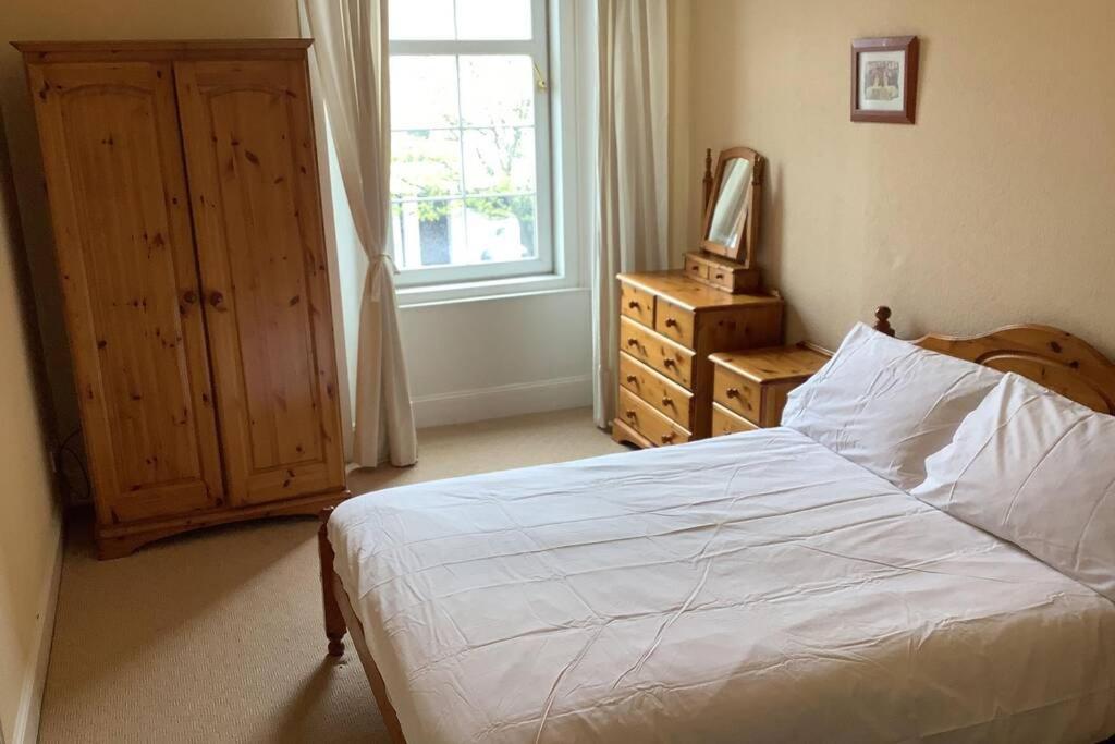 a bedroom with a bed and a dresser and a window at Ferry View in Largs