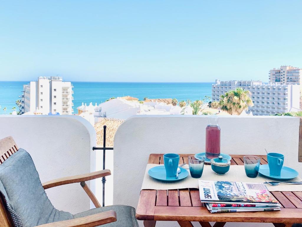 a wooden table with blue cups and drinks on a balcony at VIVE BENALMÁDENA Apartamento La Paloma, PLAYA a 100m in Benalmádena