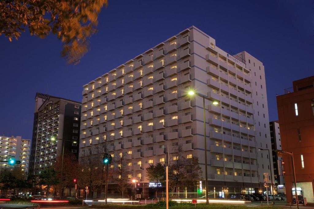 um alto edifício branco à noite numa cidade em Hotel Hakata Place em Fukuoka