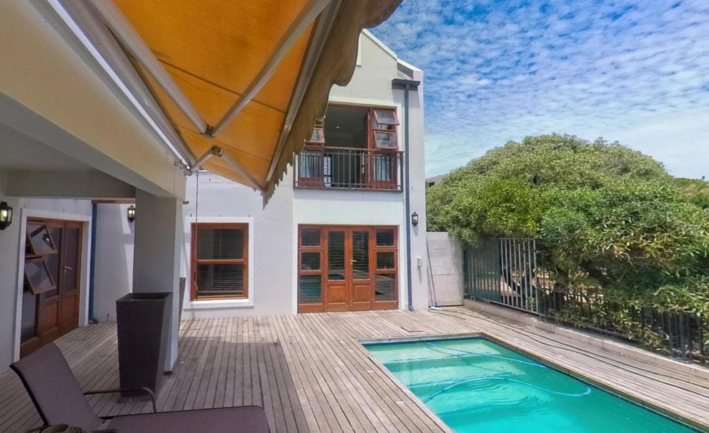 a house with a swimming pool on a deck at Blaauw Village Guest House in Bloubergstrand