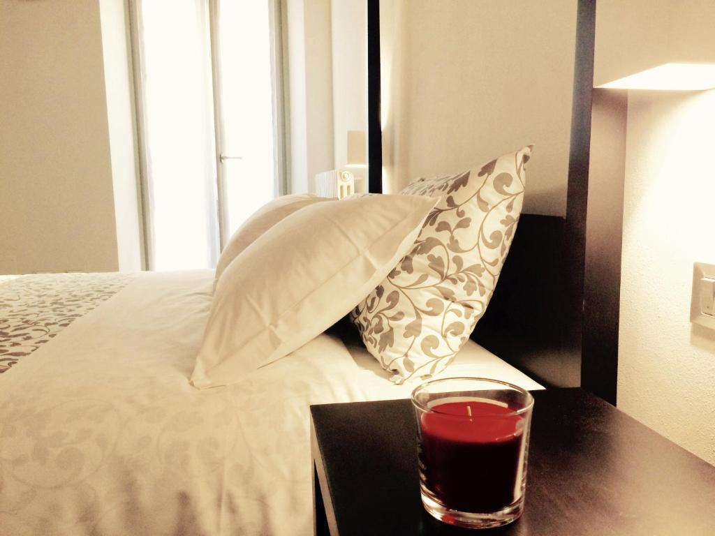 szklankę czerwonego drinka na stole obok łóżka w obiekcie Moira Rooms w Bergamo