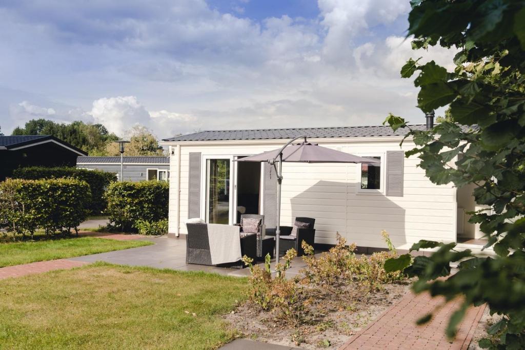 uma casa branca com um guarda-chuva e um pátio em Fazant 4 persons em Rijssen