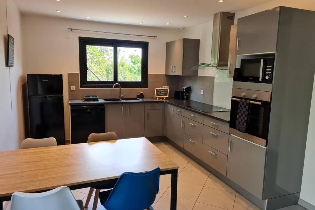 cocina con mesa de madera y sillas azules en LA CASA DE PECHABOU, en Péchabou