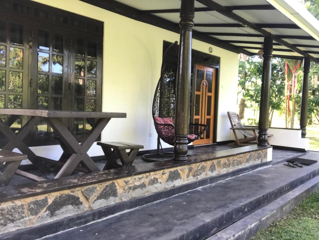 a house with a table and a surfboard on the porch at aji fruit farm in Embilipitiya