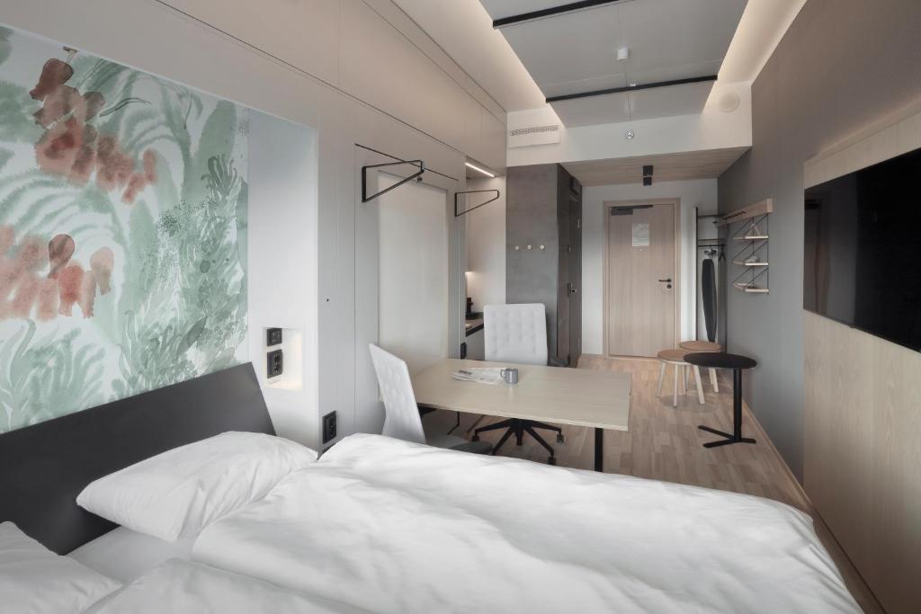a bedroom with a bed and a table and a dining room at VALO Hotel & Work Helsinki in Helsinki