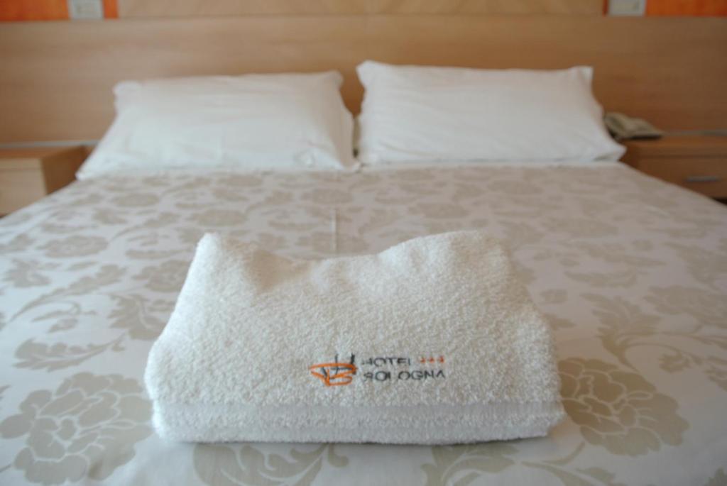 a white pillow sitting on top of a bed at Hotel Bologna in Lignano Sabbiadoro