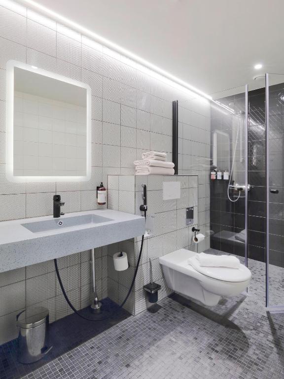 a bathroom with a sink and a toilet and a shower at VALO Hotel & Work Helsinki in Helsinki