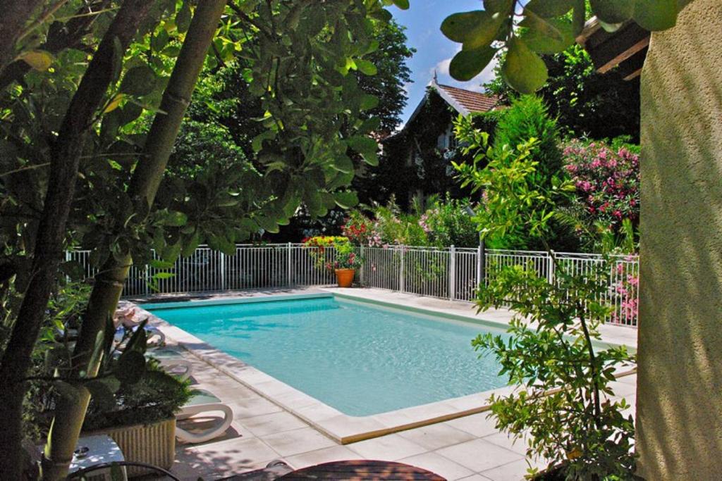 a swimming pool in a yard with trees and flowers at Hôtel le Chalet Fleuri in Saint-Rémy-de-Provence