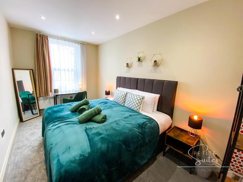 een slaapkamer met een groot bed en een blauwe deken bij The Wild Fauna Suite - Petite Suites in Peterborough